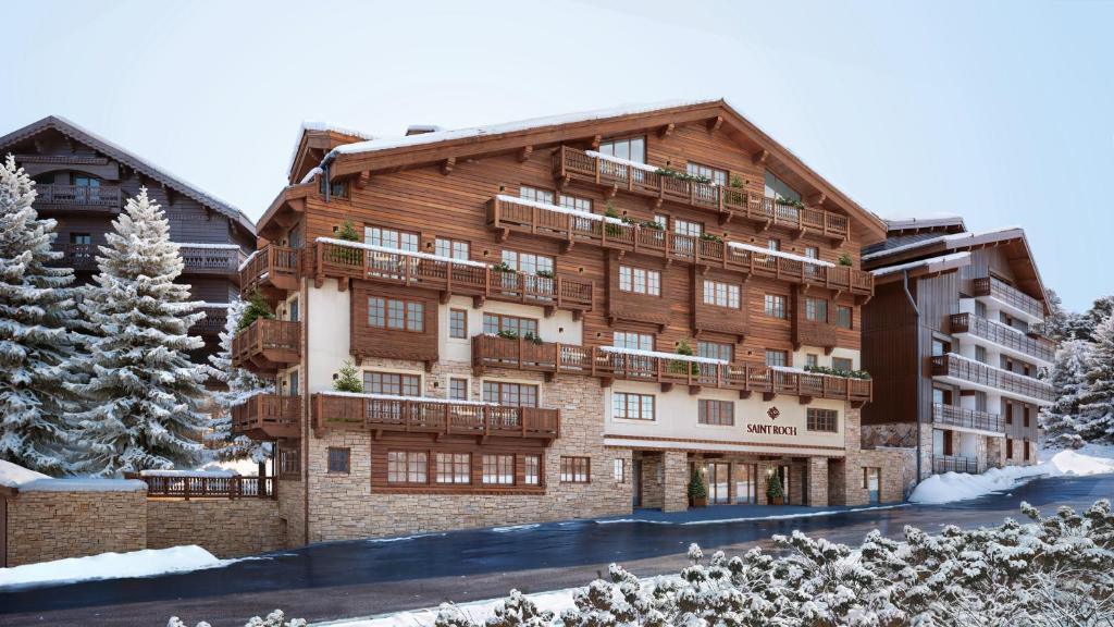 a large apartment building with snow on the ground at Hotel Saint Roch in Courchevel