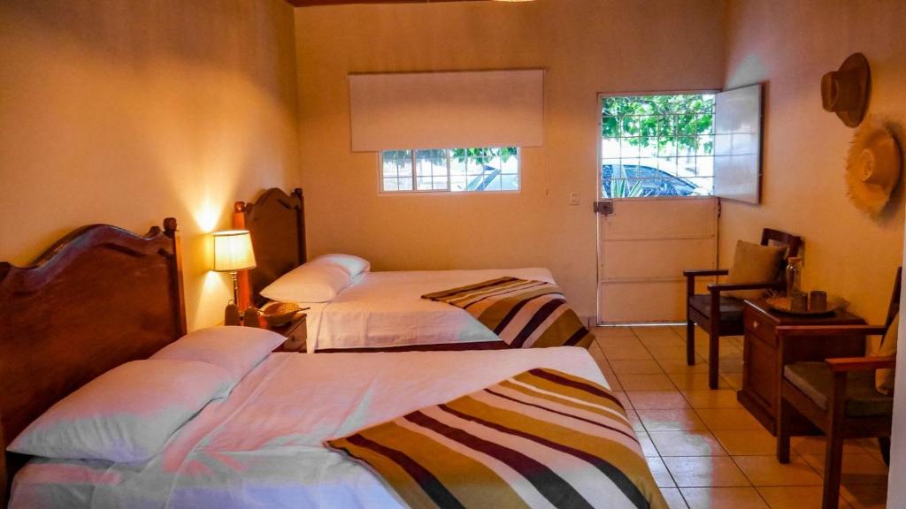 a bedroom with two beds and a desk and a window at Cien Fuegos Hostel in Salcoatitán