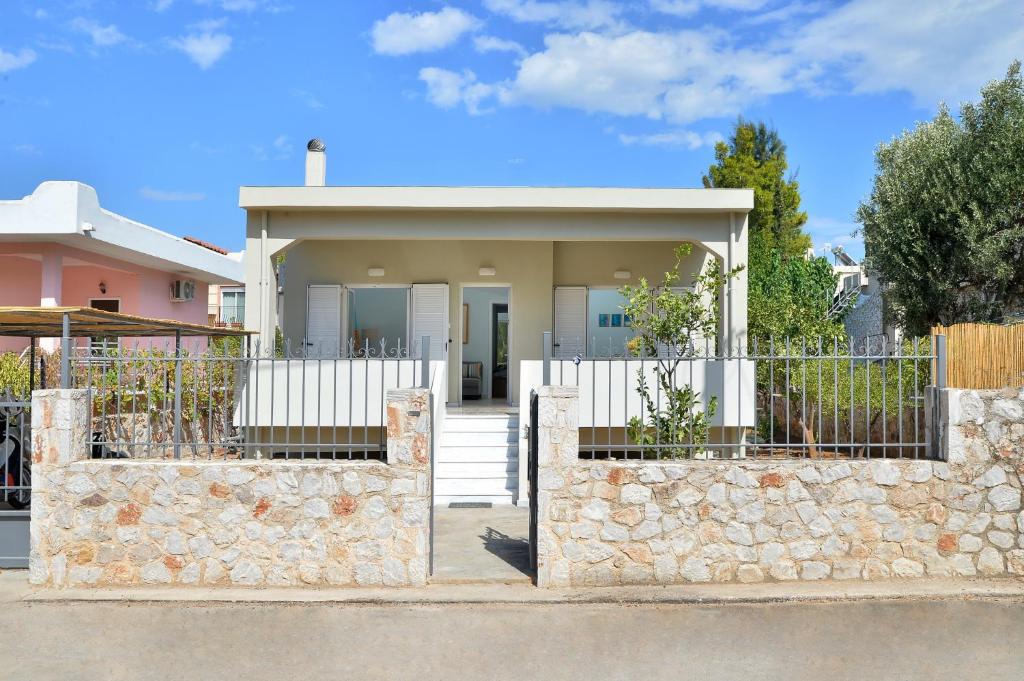 a house with a stone wall and a fence at Vottas Seaside House Nea Makri in Nea Makri