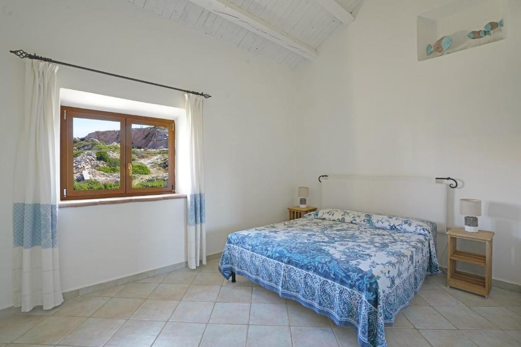 a white bedroom with a bed and a window at Appartamento il Caracolo a Cala Francese in La Maddalena