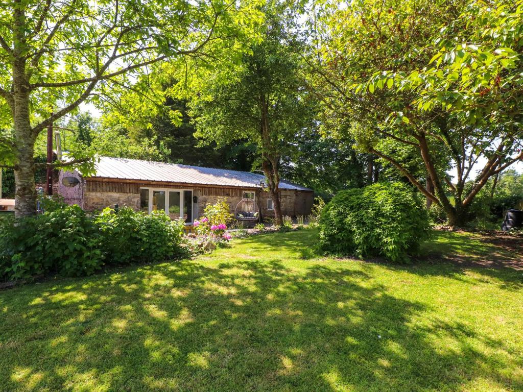 a house in a yard with trees and grass at Woodman's Lodge in Moelfre