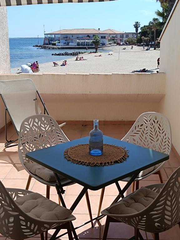 a blue table with chairs and a bottle of water on top at Les pieds dans l'eau in Mèze