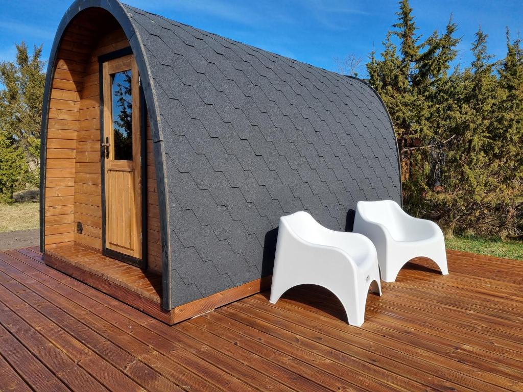 a tiny house with two white chairs on a deck at Kivipalu kämping in Allika
