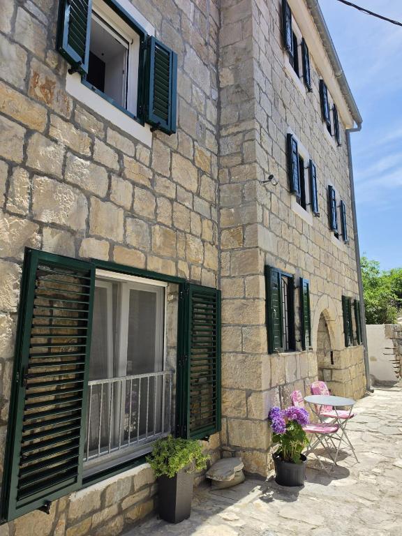 a stone building with green shuttered windows and flowers at Apartments Jelinek in Brela