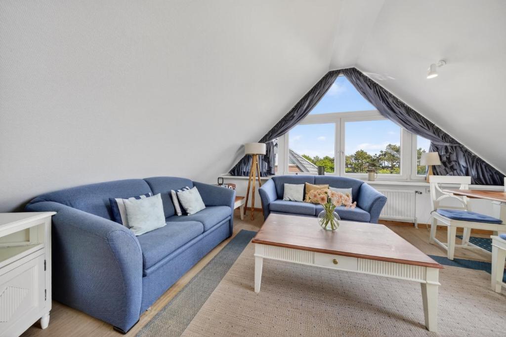 a living room with a blue couch and a table at Liiger-Hoern-DG-Wohnung-4-Moewe in Tinnum