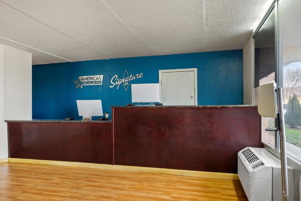 a reception desk with two computers on a blue wall at Americas Best Value Inn in Danville
