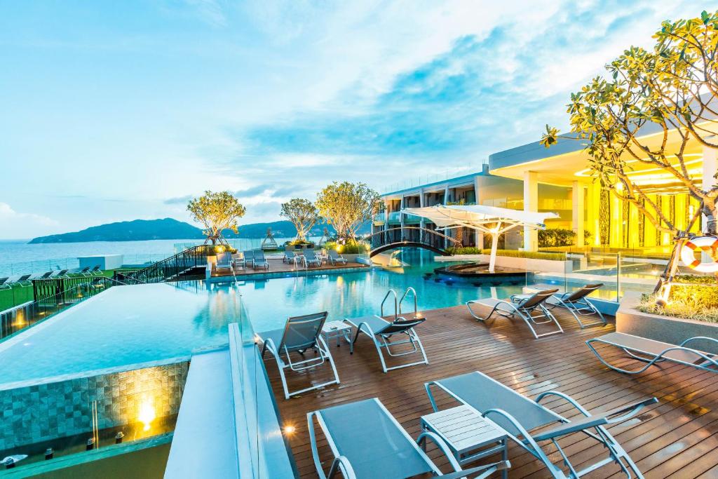 a hotel with a swimming pool and chairs on a deck at Crest Resort & Pool Villas - SHA Extra Plus in Patong Beach
