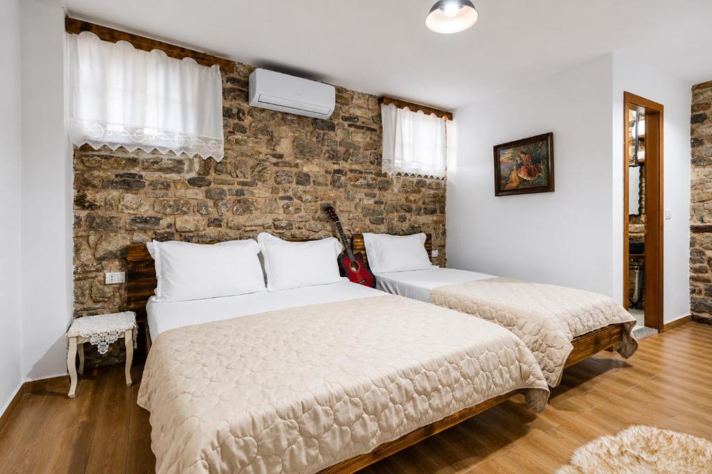 two beds in a bedroom with a brick wall at Kitarat Berat Castle in Berat