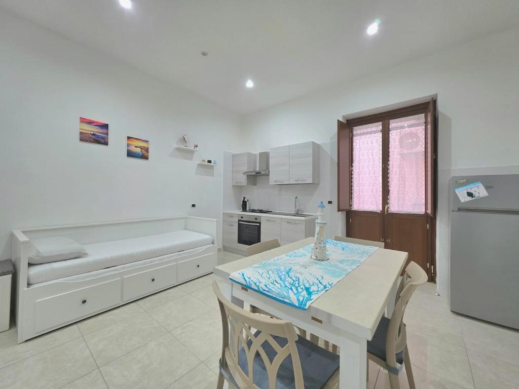a white kitchen with a table and a bench in it at Il Silenzio del Mare in Gaeta