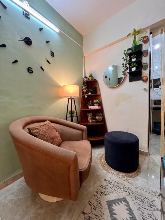 a living room with a chair and a clock on the wall at Sugar Waves in Navi Mumbai
