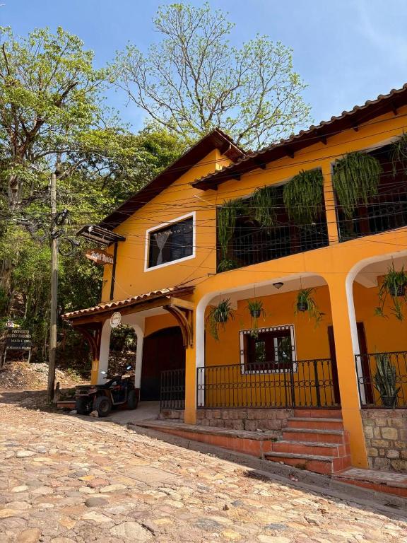 a large yellow house with a porch and stairs at Hostal Marias in Copán Ruinas