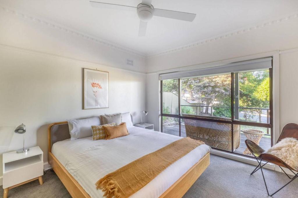 a bedroom with a bed and a large window at Hillhouse in Myrtleford