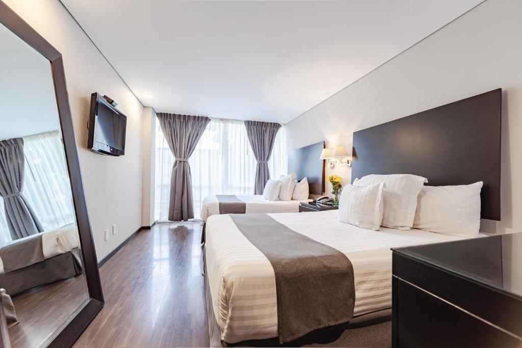 a hotel room with two beds and a flat screen tv at Suites Parioli in Mexico City