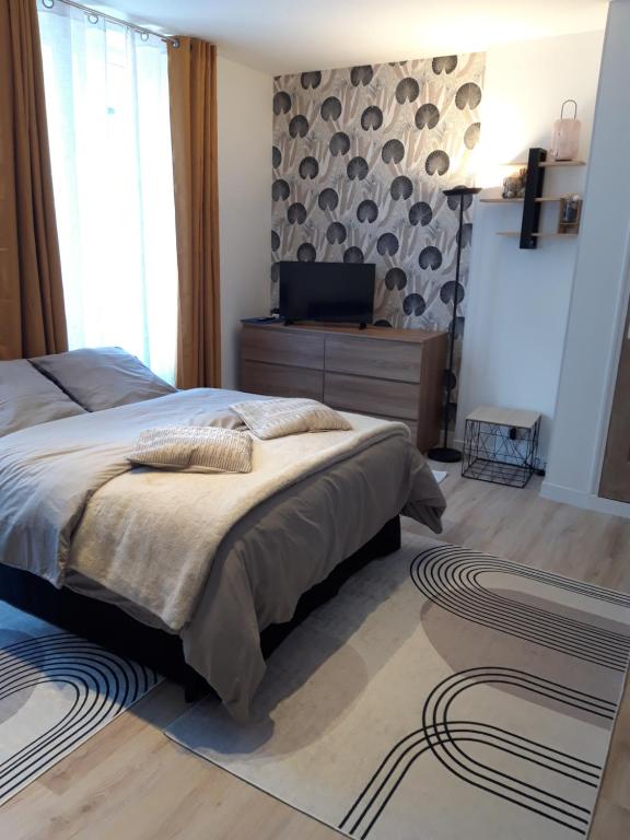 a bedroom with a bed and a television in it at TINCHEBRAY Centre ville in Tinchebray