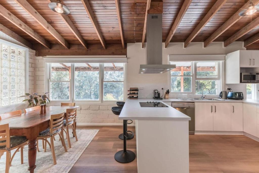 a kitchen with wooden ceilings and a table and chairs at Gangurru in Myrtleford