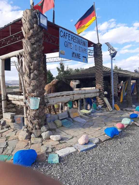 a building with a sign and a flag and rocks at Gîte d'étape Imane Café ET Restaurant in Aït Amar