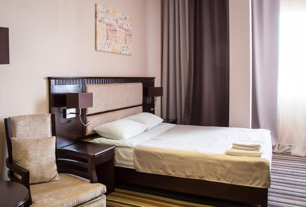 エカテリンブルクにあるGuru Hotelのベッドと椅子付きのホテルルーム