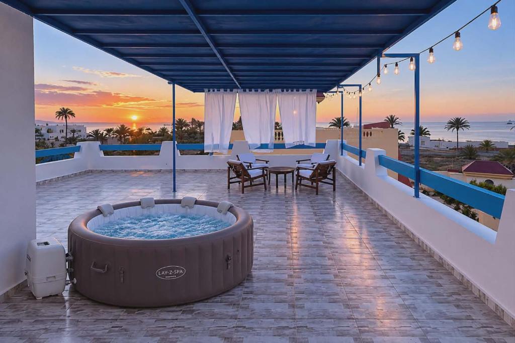 a hot tub on a balcony with a table and chairs at Villa Aura in Ouled Yaneg