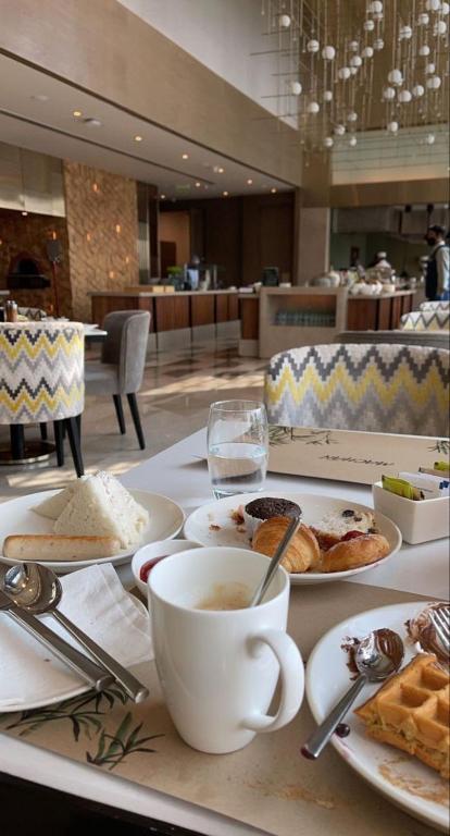 a table with plates of food and a cup of coffee at M- NET LUXURIOUS HOTEL KAGADi in Kagadi