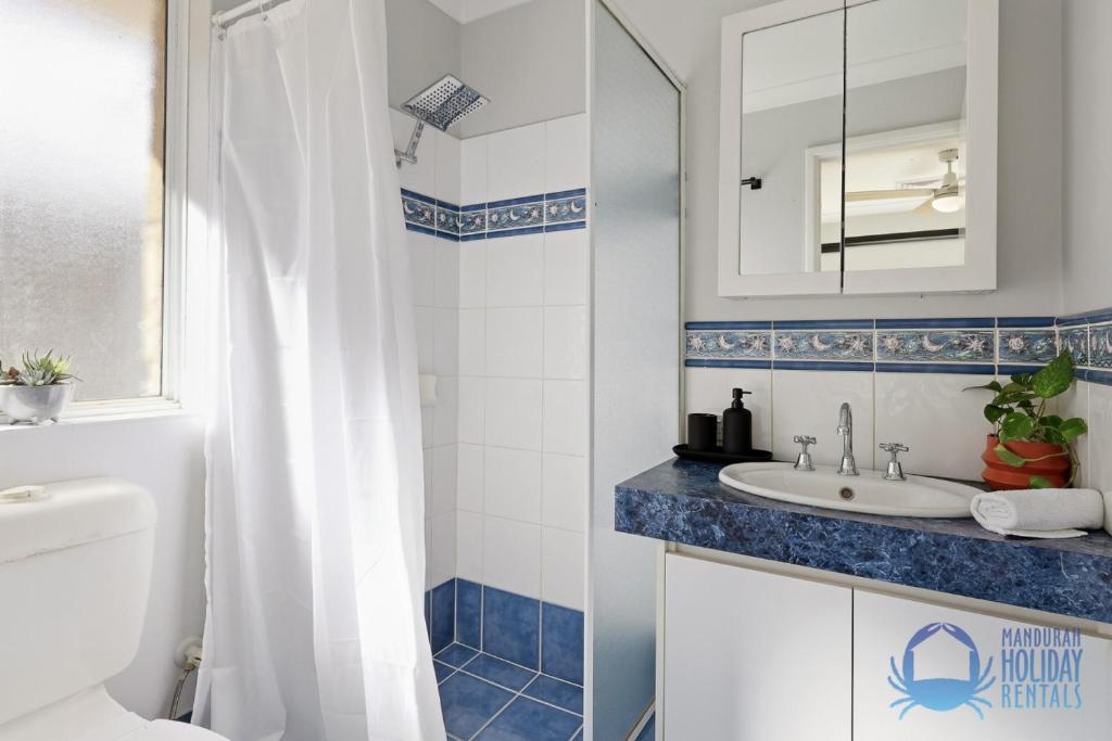 a bathroom with a white toilet and a sink at Mandurah Poolside Retreat in Coodanup