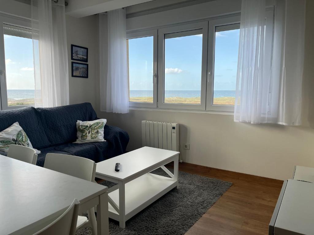 a living room with a couch and a table and windows at Barrañán Arena in Arteixo