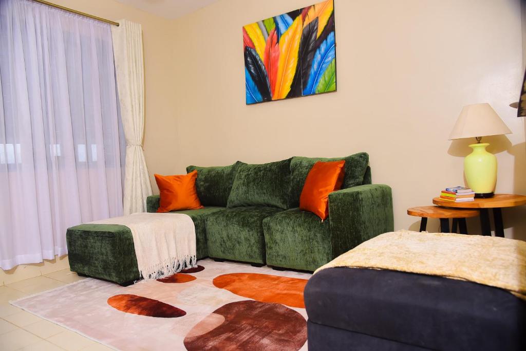 a living room with a green couch and orange pillows at Savannah suites Bel-Air in Gilgil