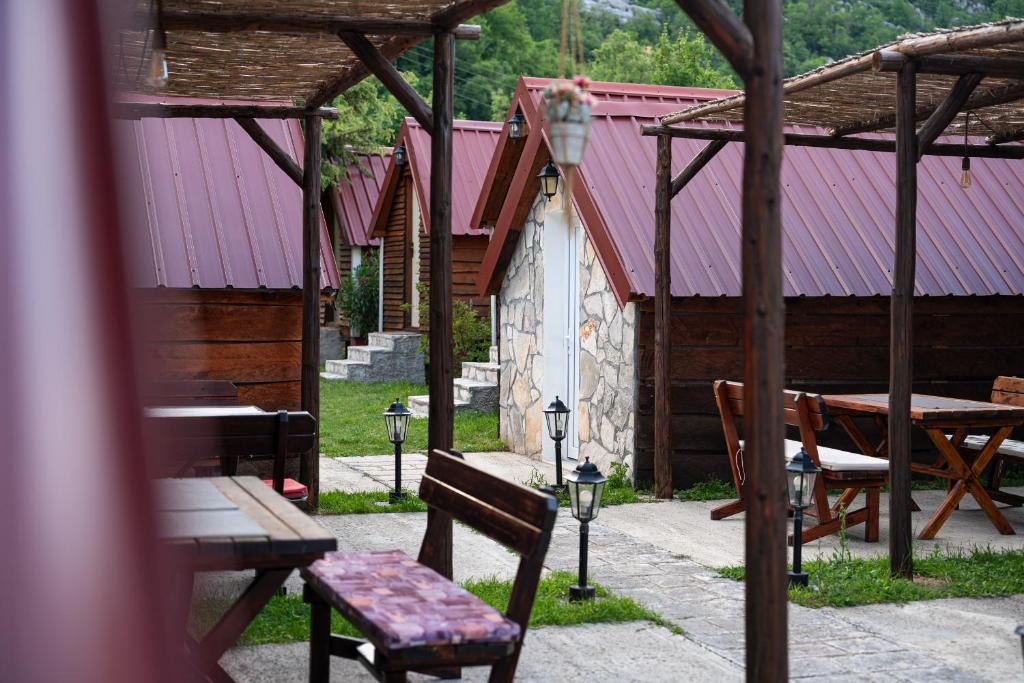 a patio with benches and a table and a building at Vikendica,Bungalovi Lipska pećina in Cetinje