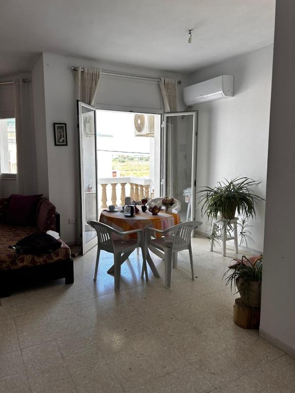 a living room with a table and chairs and a window at Appartement spacieux - Dar Chaabane plage in Nabeul