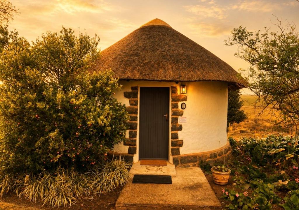 a small hut with a thatched roof and a door at The Thatched Hideaway on Stanmore farm in Nottingham Road