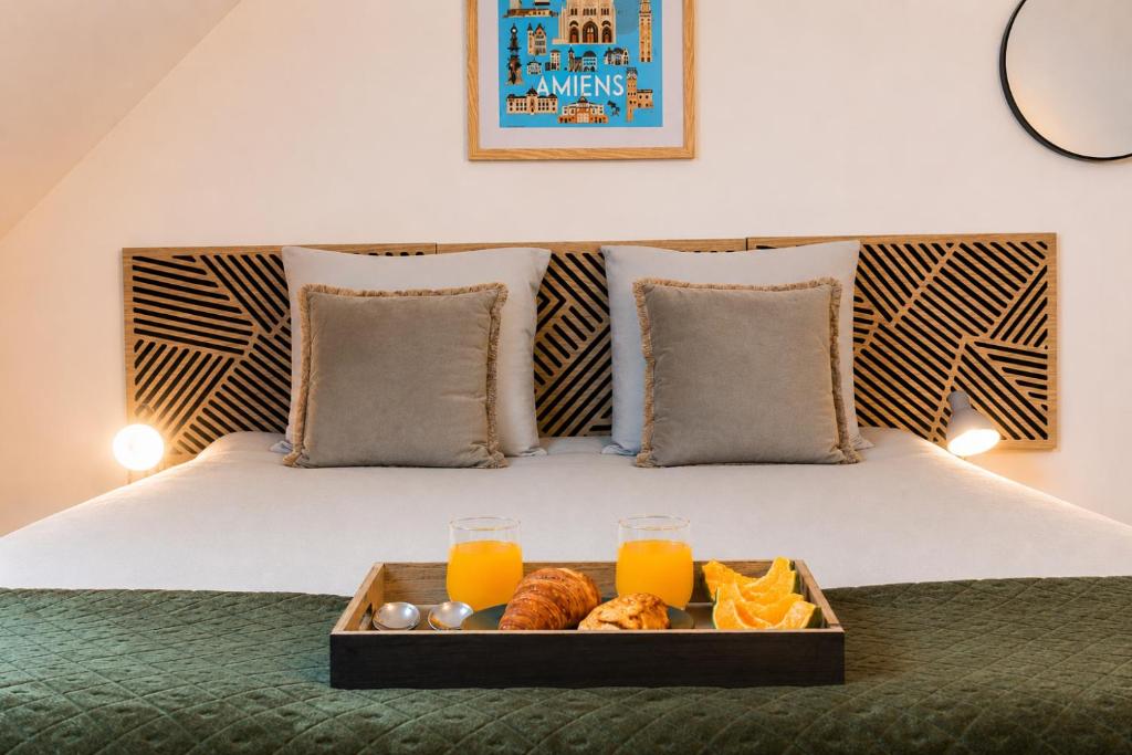a tray of food on a bed with orange juice at Le Triplex Confort I Parking gratuit I Centre Amiens in Amiens