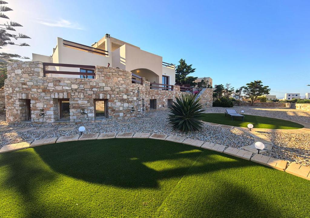 a large stone house with a green yard at PetraCasa Luxury Villa in Azolimnos Syros