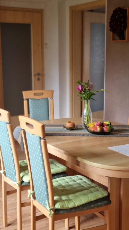 a wooden table with two chairs and a vase of flowers at Ferienwohnung Hebestreit in Kirchworbis