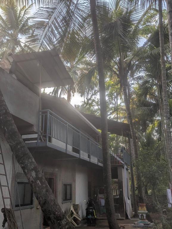 a house with palm trees in front of it at Hindlekar home stay in Malvan