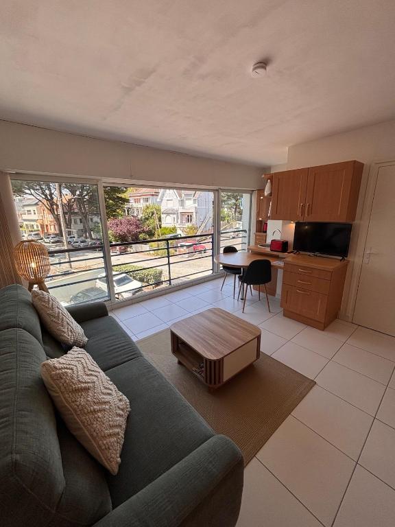 a living room with a green couch and a kitchen at Ti Gon - Le Cabanon Baulois in La Baule