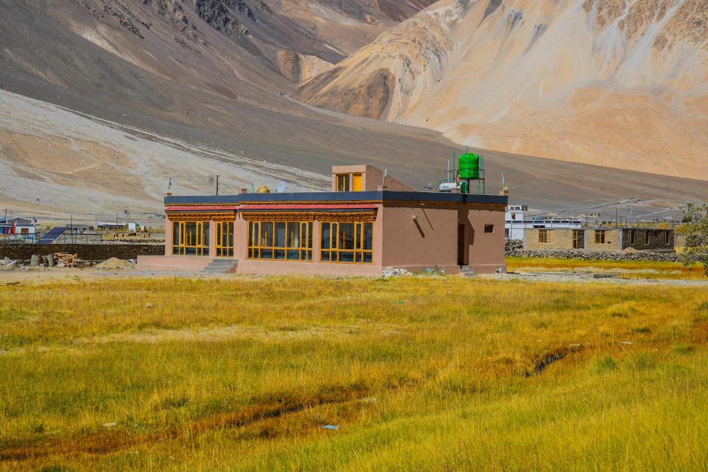 a building in a field in front of a mountain at Eco Residence Pangong in Lukung