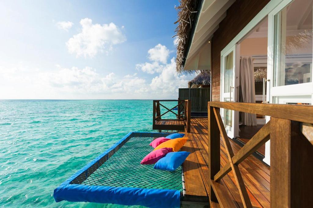 un porche con almohadas coloridas en el agua en Sun Siyam Vilu Reef with Free Transfer en Dhaalu Atoll