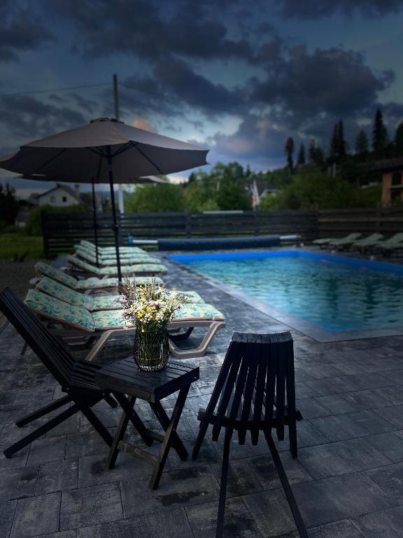 a table with an umbrella next to a pool at Kvitkovyi Rai З червня басейн з підігрівом 10 на 5 метрів in Slavske