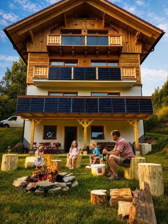 a family sitting around a fire in front of a house at Chalet Leni in Schladming