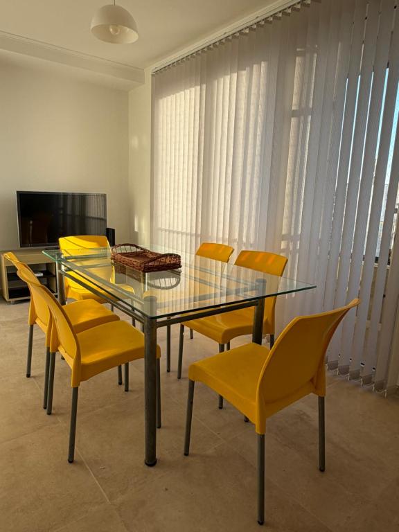 a dining room with a glass table and yellow chairs at Moras Urban in Esperanza