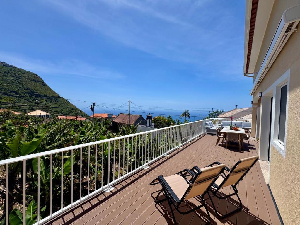 a balcony with chairs and a table and the ocean at Casa Neves in Arco da Calheta