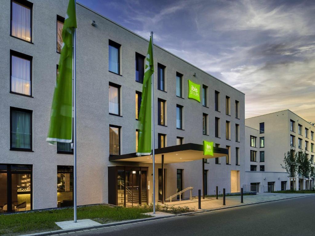 a building with green flags in front of it at ibis Styles Friedrichshafen in Friedrichshafen