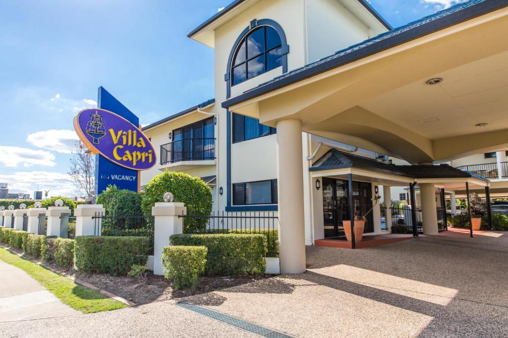 
a large white house with a sign on the front of it at Villa Capri Motel in Rockhampton
