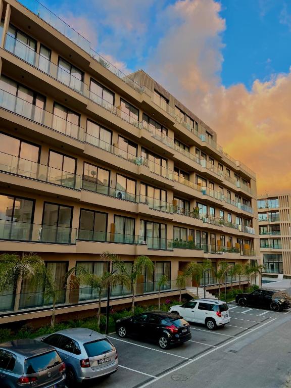 a large building with cars parked in a parking lot at Lunea Apartment Palm Residence in Vlorë