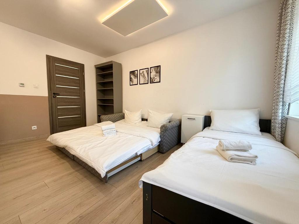 two beds in a room with white sheets at Park Leśnicki Homely Studios by BookingHost in Wrocław