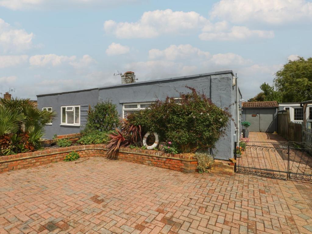a gray house with a brick driveway in front of it at Bay Cosy in Pevensey