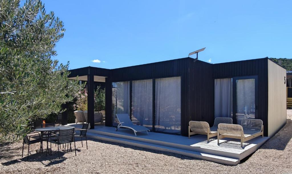 a black house with chairs and a table at Jazine BeachVilla5 in Tisno
