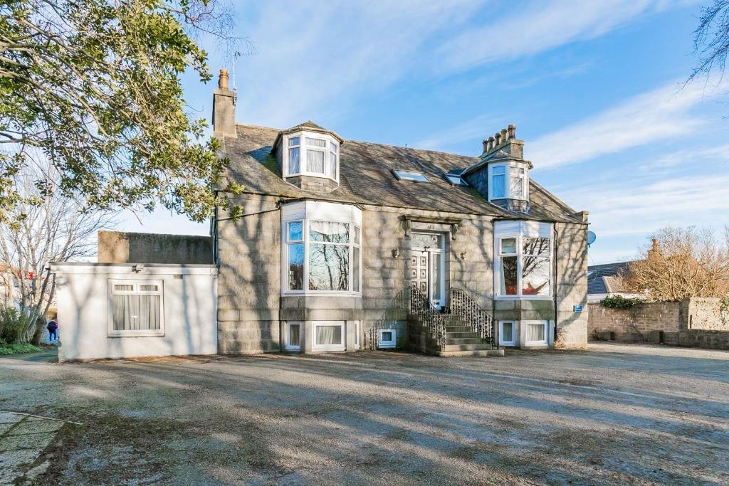 an old stone house with a large driveway at Station View Guest House in Dyce
