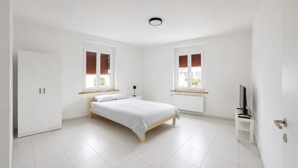 a white bedroom with a bed and two windows at DreamWork Point Grenchen in Grenchen