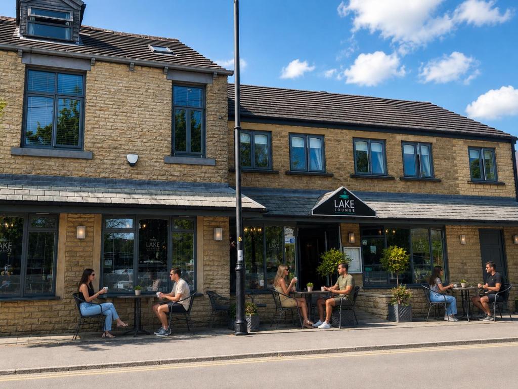 a group of people sitting at tables outside a building at Lake Lounge Rooms in Littleborough