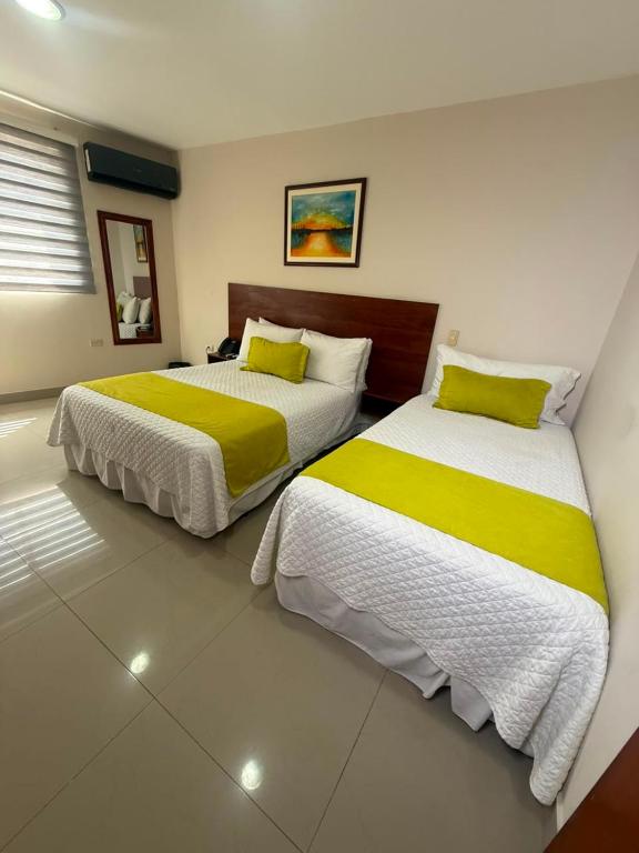 two beds with yellow and white sheets in a room at Marina Breeze hotel in Manta